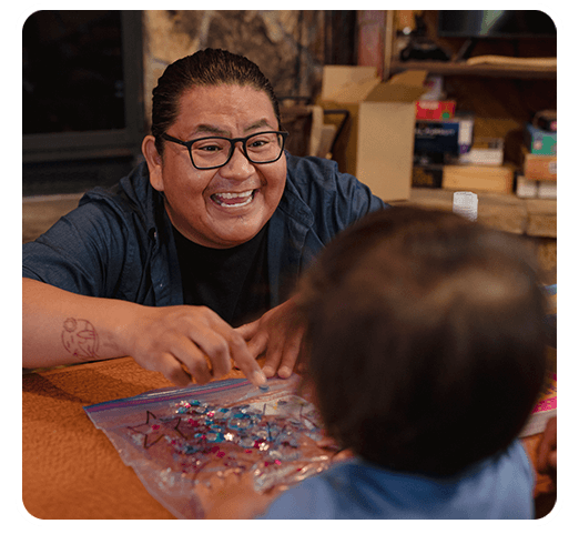 Decorative photo of Byrickson smiling at a toddler while doing crafts together.