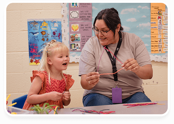 Decorative photo of Mikala doing crafts with a young child, both smiling.