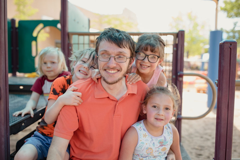 Alex Miller, educador de la primera infancia, posa con sus estudiantes en un parque infantil.