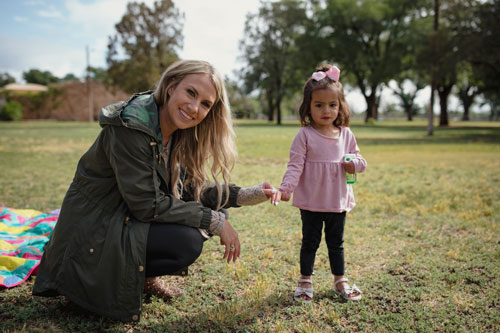 Developmental Specialist Robyn Marton poses with a toddler outdoors